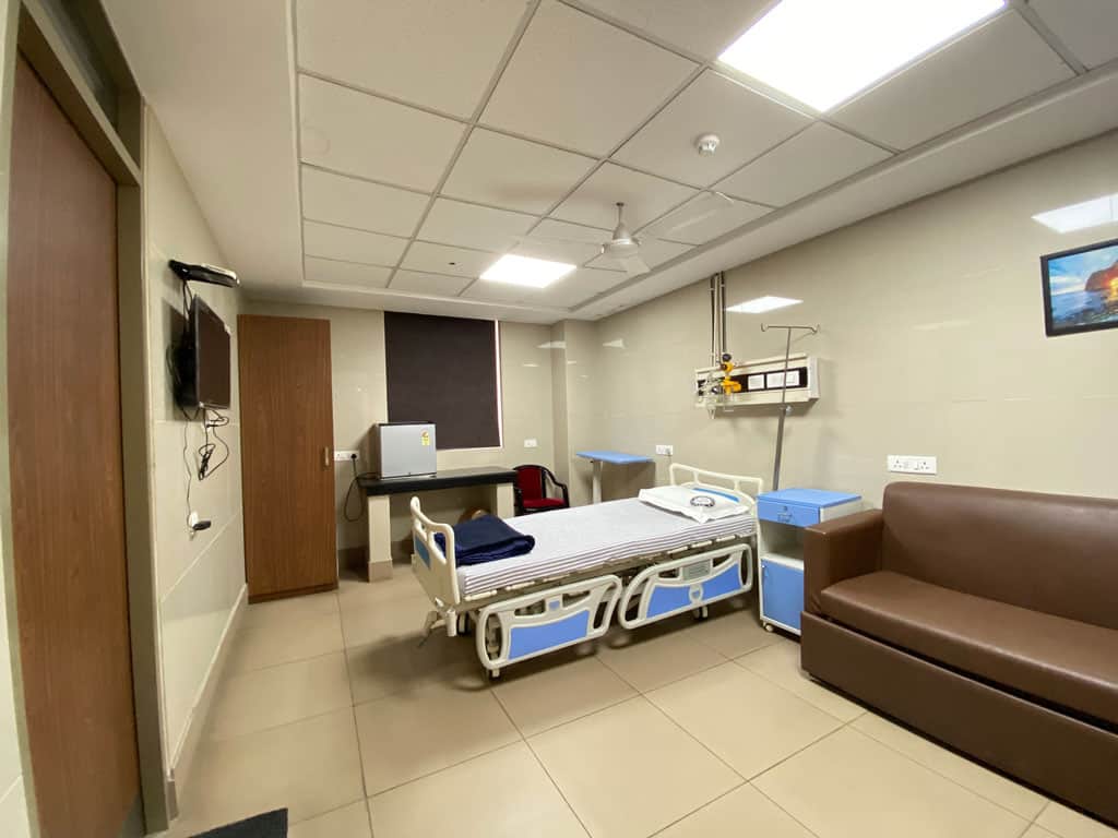 Modern hospital room with medical equipment and comfortable seating for patient care.