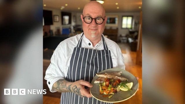 Chef presents dish with vegetables and fish.