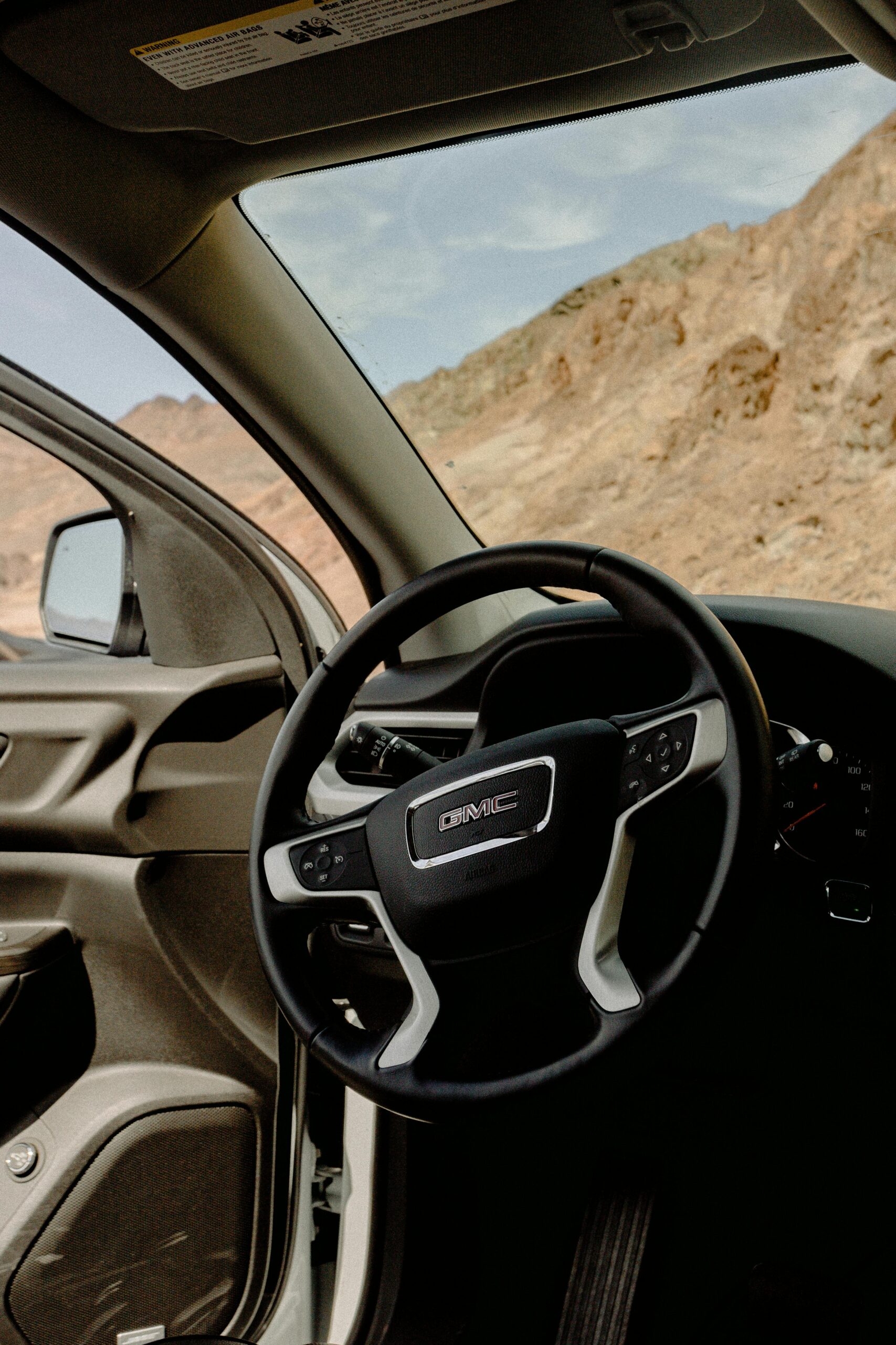Interior view of a General Motors vehicle showing the steering wheel and dashboard, with a scenic desert landscape outside. Perfect for auto maintenance and repair services.