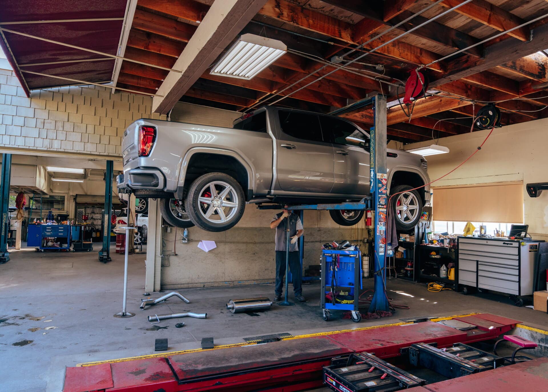 Professional vehicle repair service at Del Mar Car Care, featuring a lifted truck on a hydraulic lift in a well-equipped auto shop.