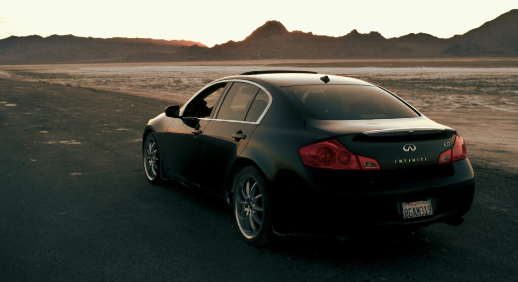 Infiniti car parked on desert road at sunset, showcasing luxury vehicle maintenance and detailing services.