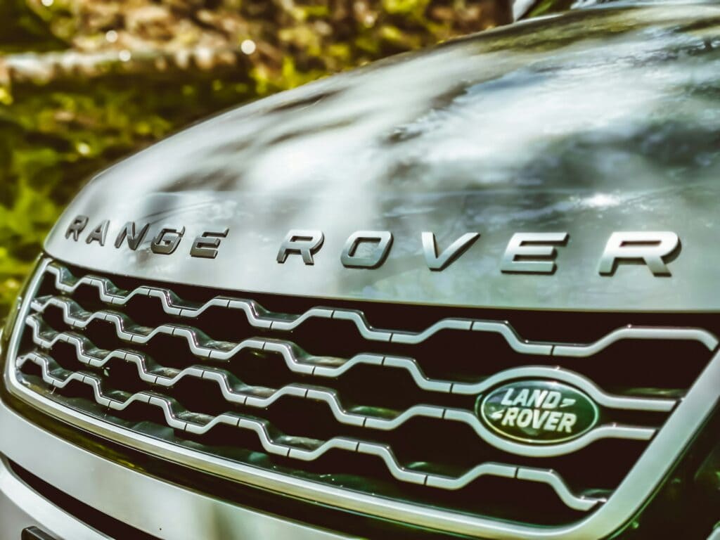 Close-up of a Land Rover vehicle's front grille showcasing the iconic logo and design, emphasizing luxury and off-road capability.