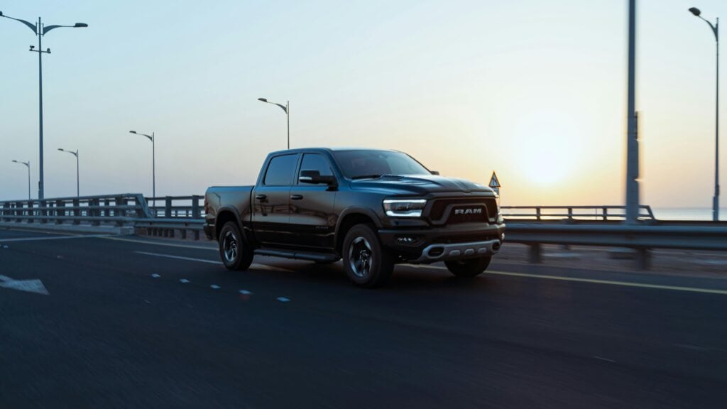 Black Ram pickup truck driving on the highway during sunset, showcasing its powerful design and performance. Perfect for automotive enthusiasts and truck lovers.