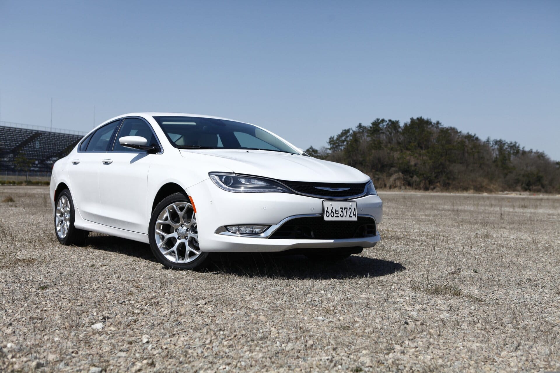 White Chrysler sedan parked on a gravel lot, showcasing vehicle maintenance and repair services at Del Mar Car Care.