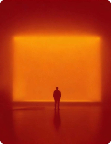 Person viewing an illuminated orange art installation at Denali Development.