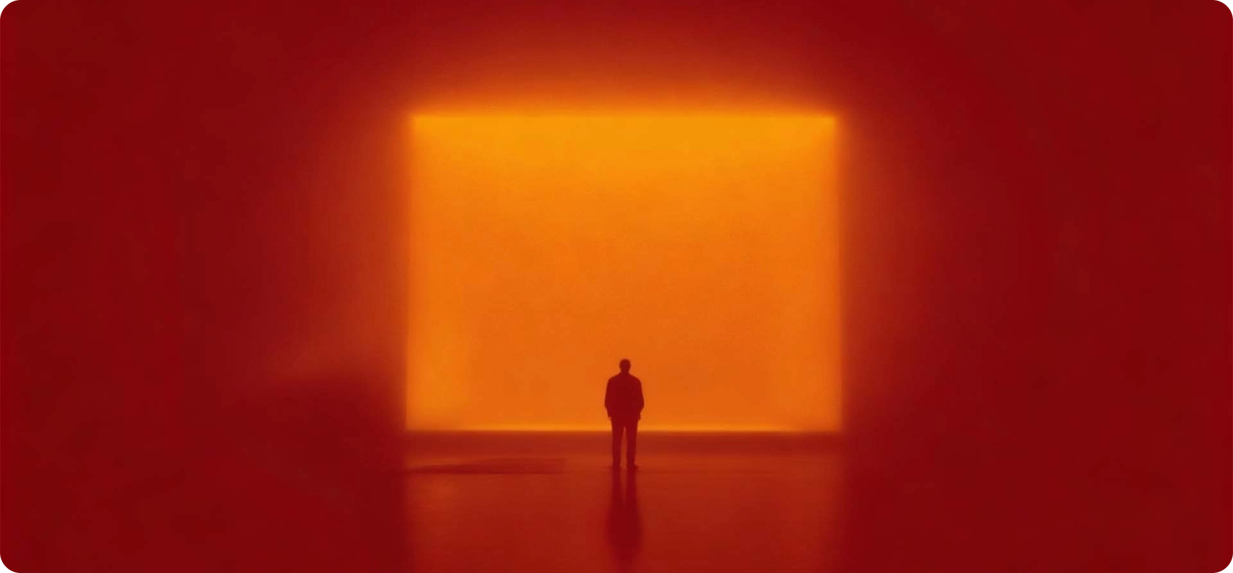 Person standing in front of a large glowing orange square art piece.