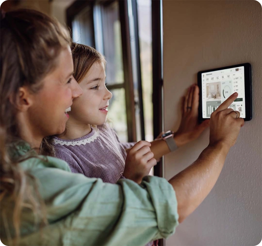 Family interacting with a smart home control panel on the wall.
