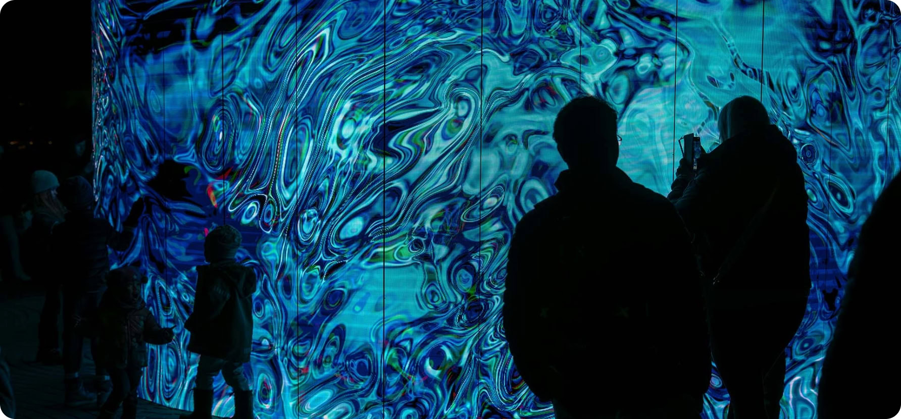 Visitors engaging with a vibrant, swirling digital art display at a cultural space.