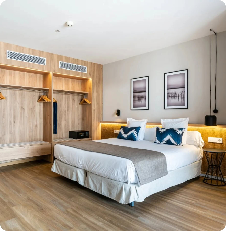 Contemporary hotel room with a large bed, wooden accents, and minimalist decor.