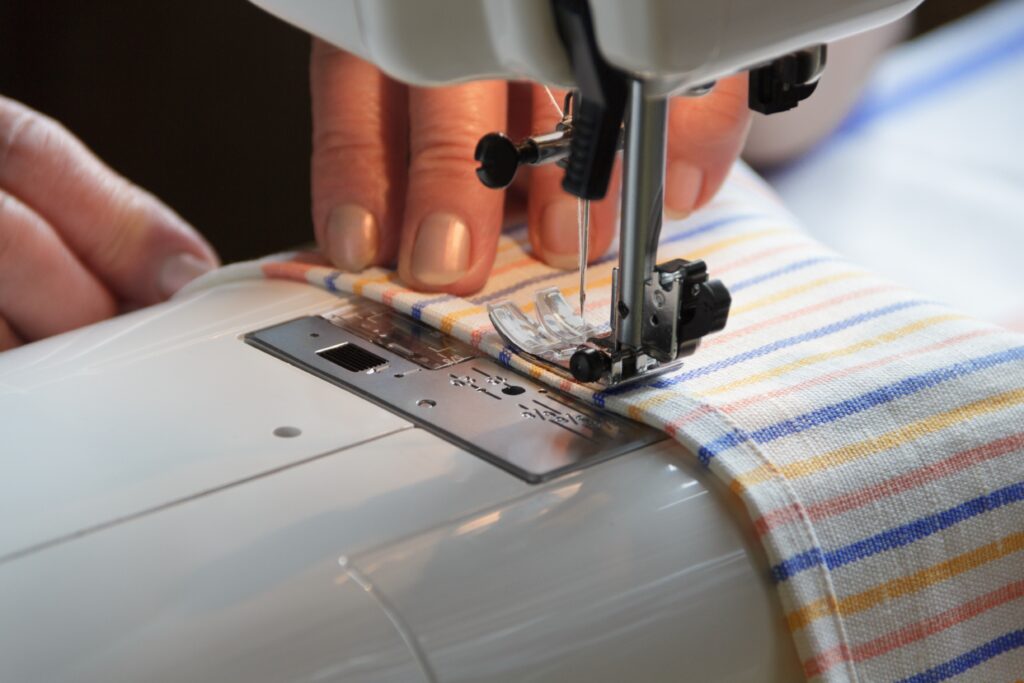 Skilled seamstress crafting bespoke drapery panels in local workroom.