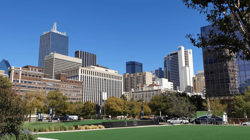 Downtown Dallas Texas skyline with modern skyscrapers and office buildings, urban cityscape, vibrant city view, and clear blue sky, highlighting real estate and property market opportunities.