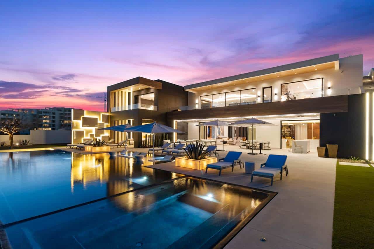 A Pool With Chairs And A Building With A Purple Sky