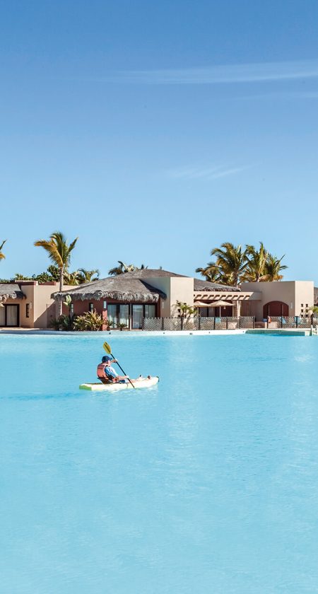 Kayaking By Diamante Beaches And Pools – Pacific Ocean Adventure A Man Kayaking In The Pacific Ocean Near Diamante Beaches And Pools, With The Resort’s Golden Dunes And Coastline In The Distance.