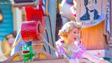 Rapunzel and Pascal from Tangled delight fans in a vibrant Disney parade, with a Flynn Rider poster adding to the fairytale fun.