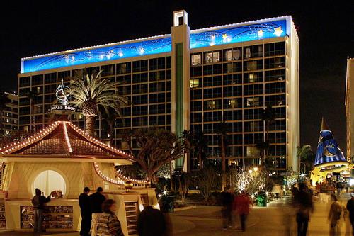 Disneyland Hotel at night with a vibrant blue mural on the roof and a glowing kiosk, offering an immersive Disney resort vibe.