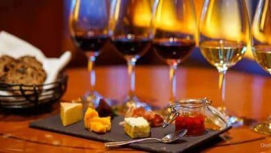 A whimsical wine flight with cheeses, bread, and preserves served at a Disney Springs eatery, glowing under festival lights.