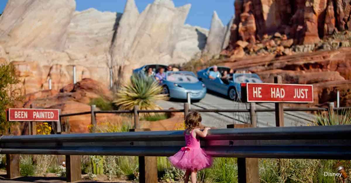 A child in a pink dress enjoys Radiator Springs Racers, watching Lightning McQueen and friends speed through Cars Land.