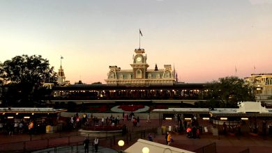 Guests gather outside Magic Kingdom’s Main Street train station, basking in a golden sunset as the park prepares for evening magic.