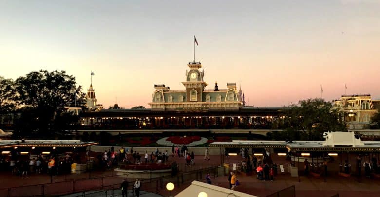 Guests gather outside Magic Kingdom’s Main Street train station, basking in a golden sunset as the park prepares for evening magic.