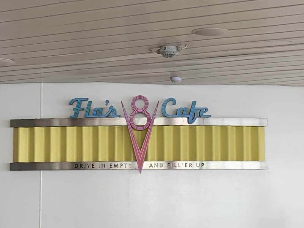 Flo’s V8 Cafe retro sign pops against a yellow and white wall, channeling Cars Land nostalgia like on board The Disney Fantasy.