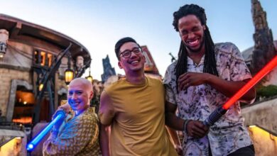 Guests pose with toy lightsabers at sunset during Star Wars Nite at Disneyland After Dark, immersed in galactic décor.