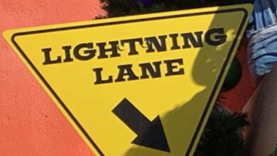 Lightning Lane yellow triangle sign with black arrow, pointing Disneyland fans to their next Genie+ adventure.