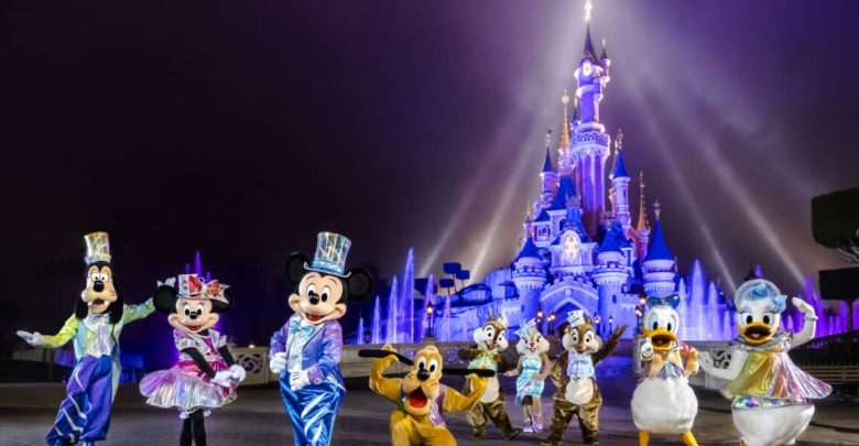 Beloved Disney characters gather in front of Cinderella Castle, aglow with dazzling purple and blue lights during a magical night.