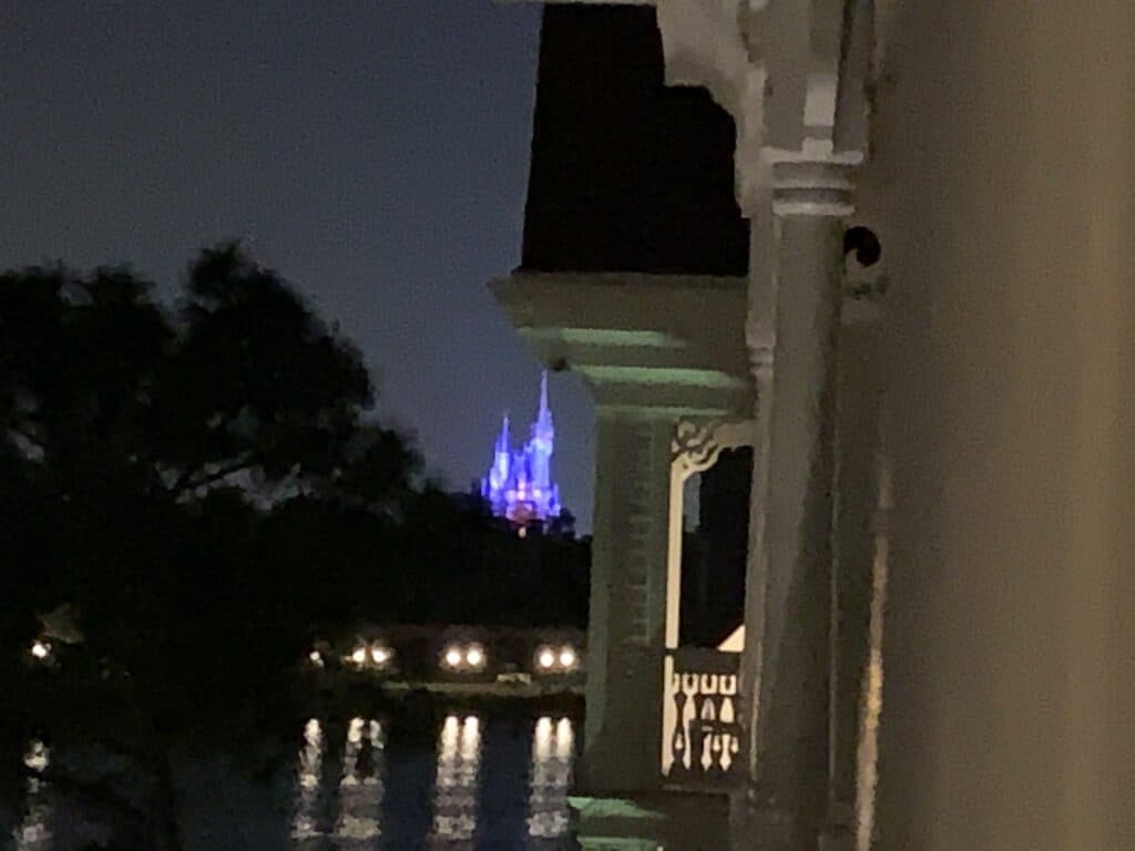 Cinderella Castle glows blue at night across the lake, evoking Disney Enchantment just outside Magic Kingdom.