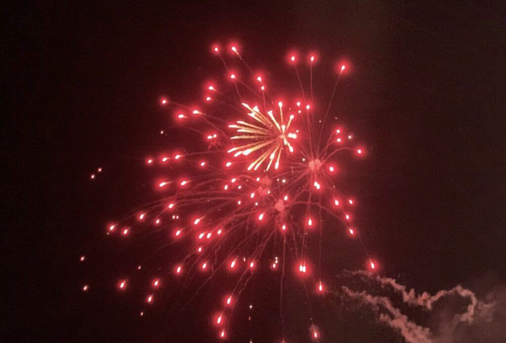 Brilliant red fireworks explode above the Disney Fantasy, illuminating the night sky in a dazzling show at sea.