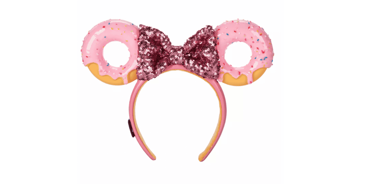 Part of the Mickey Mouse Donut Collection, this headband features two pink frosted donut shapes with sprinkles as ears and a sparkly, dark pink bow in the center. The headband itself is pink with yellow-tinted edges.