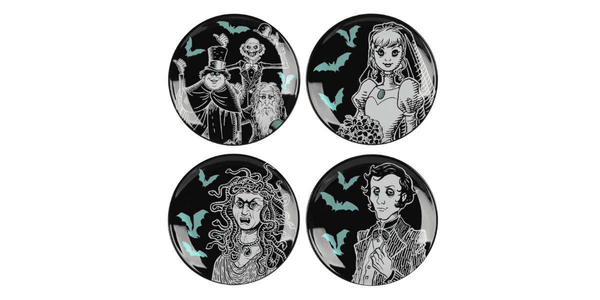 An image of four Halloween-themed plates from the Haunted Mansion Kitchen Collection, each featuring a different black and white drawing of spooky characters against a dark background with flying bats. The characters include a man with a top hat, a ghostly bride, a woman with wild hair, and a man in a suit.