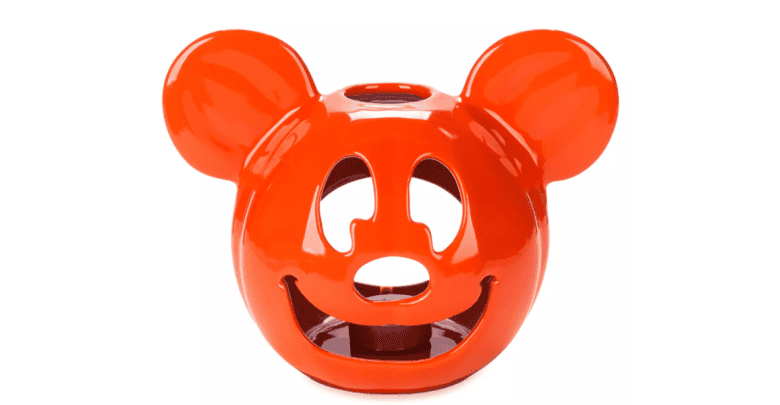 A bright orange ceramic candle holder shaped like the head of a cartoon mouse, with cutouts for the eyes, nose, and mouth. The design is playful and has two round ears protruding from the top.