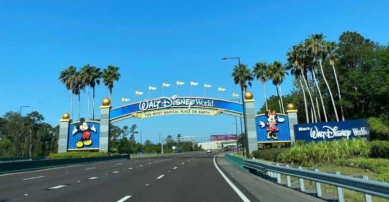Disney World entrance gate features vibrant Mickey and Minnie Mouse signs, greeting guests arriving for a magical day.