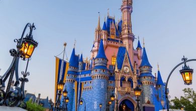 Cinderella Castle at Disney World glows in vibrant blue and gold, its lanterns illuminating the iconic park at twilight.