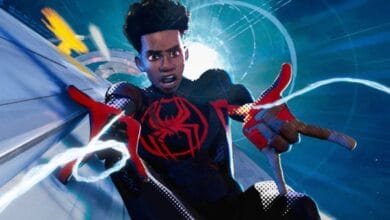 Spider-Man in his black and red Miles Morales suit swings above a neon-lit cityscape, evoking thrilling theme park adventures.