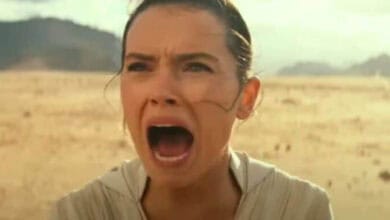 Rey, with her signature bun hairstyle, stands in a vast desert landscape at Galaxy’s Edge, passionately shouting with her mouth wide open.
