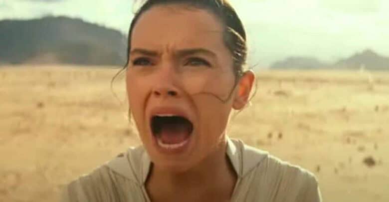 Rey, with her signature bun hairstyle, stands in a vast desert landscape at Galaxy’s Edge, passionately shouting with her mouth wide open.