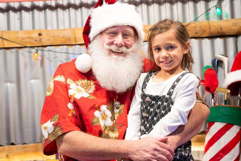 Santa Claus with young girl during Christmas celebration, festive holiday spirit.
