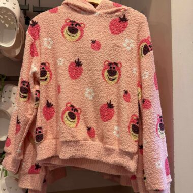 Colorful pink hoodie with fun bear and strawberry patterns from Disney fashion line.