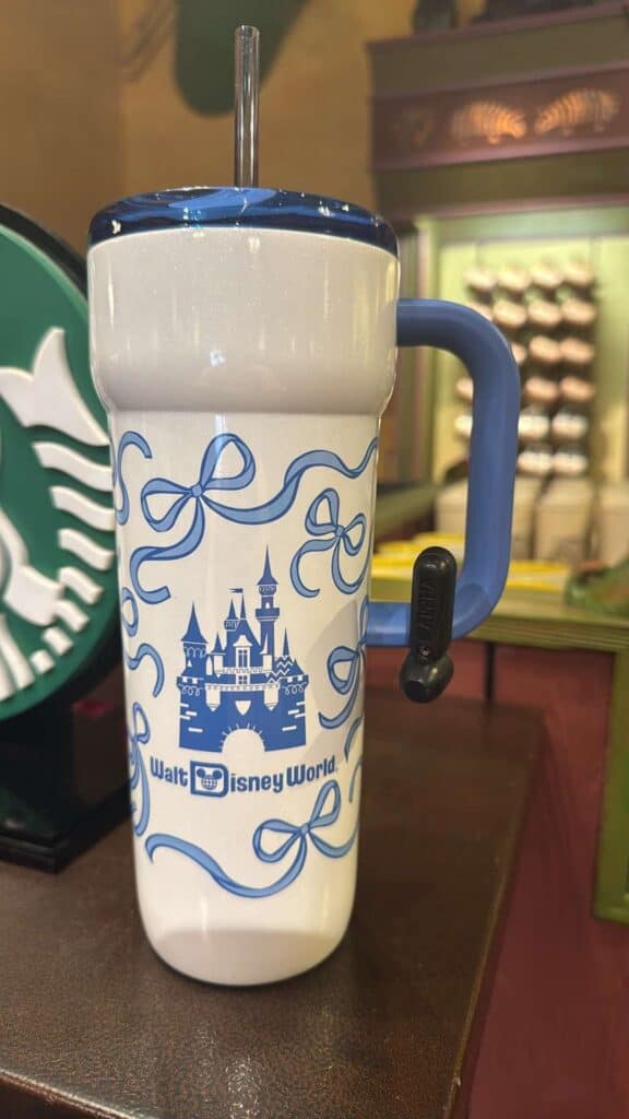 Disney theme park souvenir travel mug with castle and bow design.