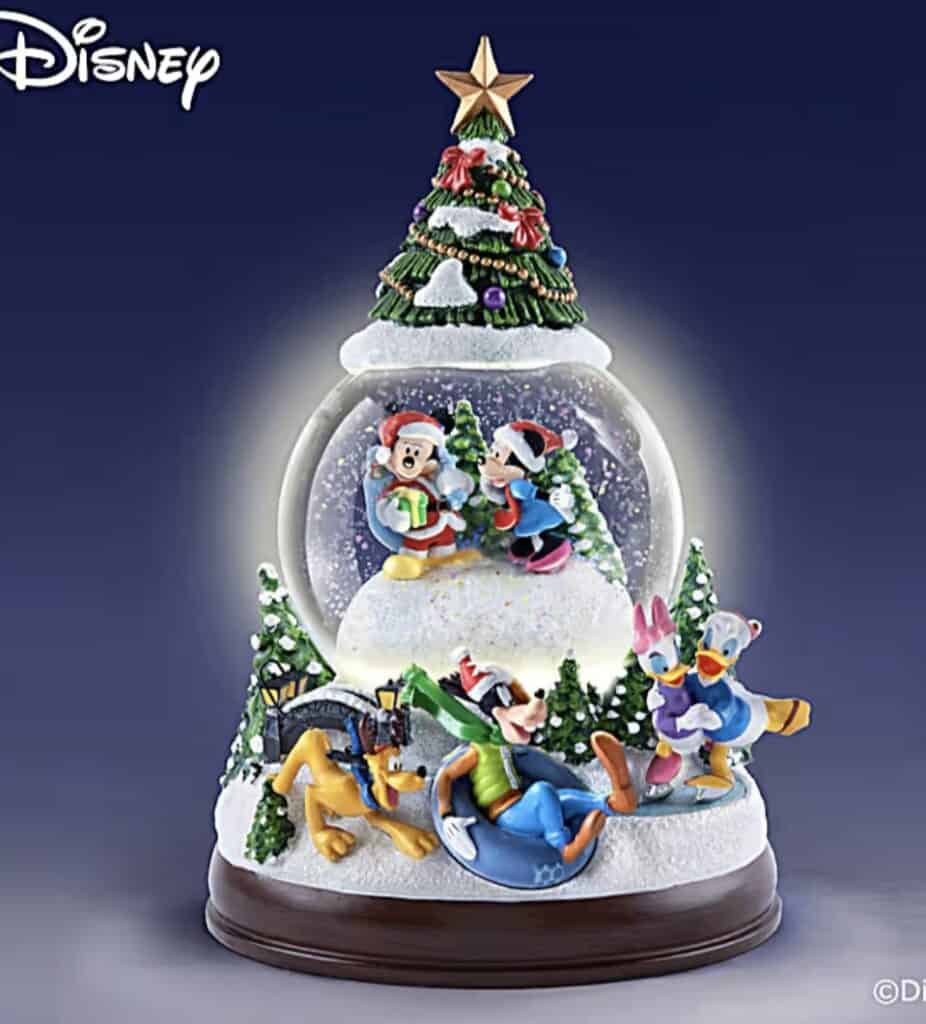 Festive Disney Christmas snow globe featuring Mickey, Minnie, Donald, Daisy, and Goofy with holiday decorations.