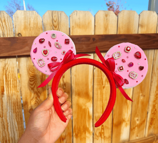 Adorable pink Minnie Mouse ears headband with gemstones and bows, perfect for Disney fans.