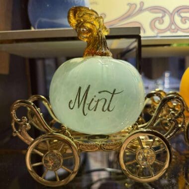 Elegant mint-green glass ornament shaped like a carriage with “Mint” inscribed, ideal for Disney-themed home décor or collectibles.