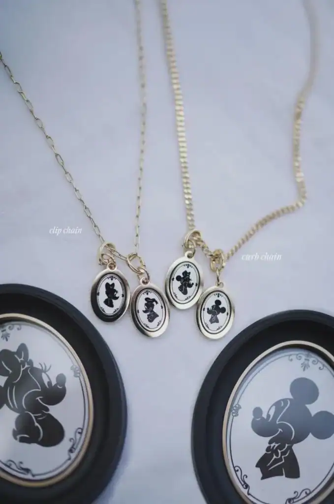Delicate gold chain necklace with Mickey and Minnie silhouette pendants, perfect for Disney fashion lovers.