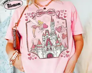 A pink Disney princess T-shirt featuring a castle graphic and Tinker Bell illustration, perfect for Disney fans.