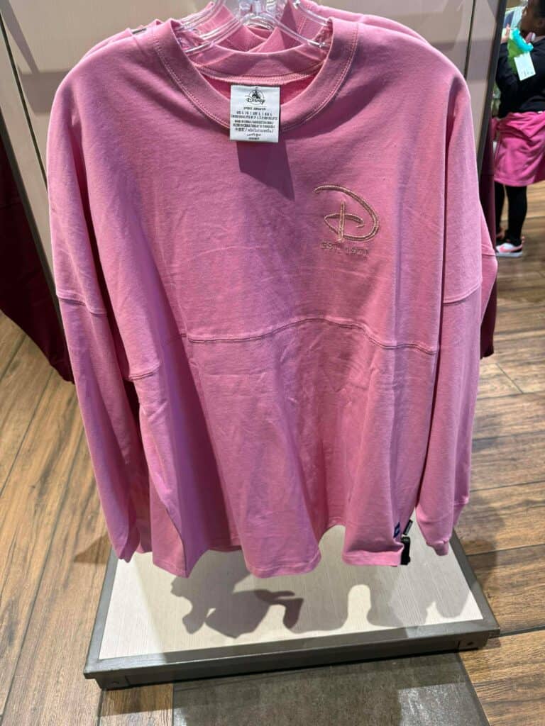 Pink Disney sweatshirt featuring embroidered logo, perfect casual fashion for Disney fans.