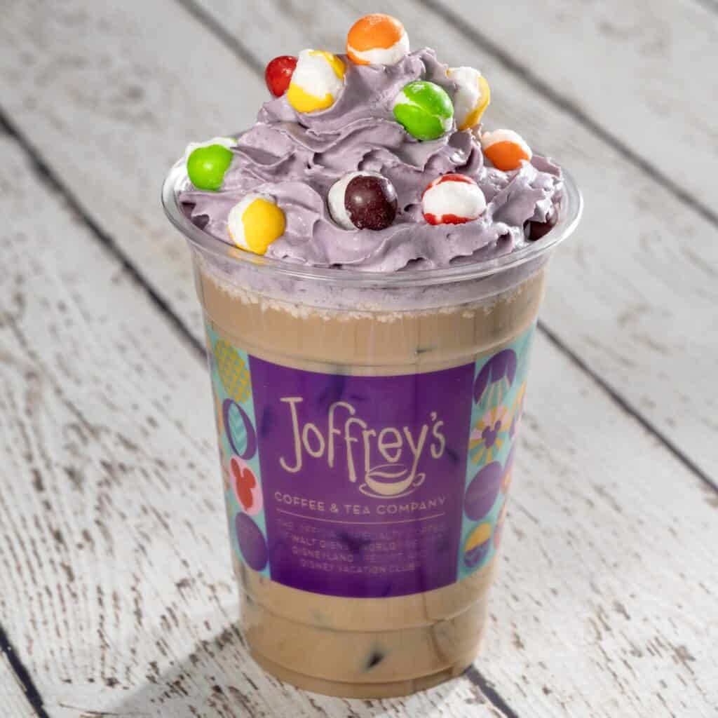 Vibrant Disney coffee beverage with purple whipped cream and colorful candy toppings, ideal for Disney enthusiasts.