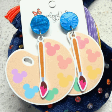 Vibrant blue, rainbow Mickey Mouse shaped earrings with a paintbrush dangle design. Perfect accessory for Disney fans.