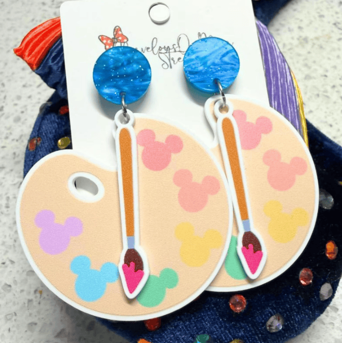 Vibrant blue, rainbow Mickey Mouse shaped earrings with a paintbrush dangle design. Perfect accessory for Disney fans.
