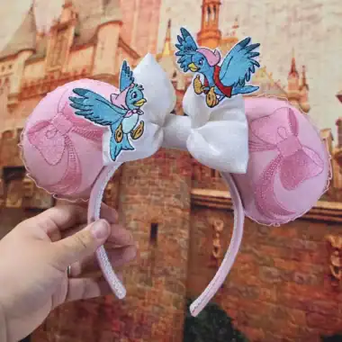 Vintage-inspired Disney Minnie Mouse ears headband featuring embroidered Daisy Duck patches and pink satin bows.